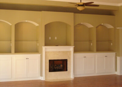 Built-in white cabinets flanking a small gas fireplace in a tan living room.